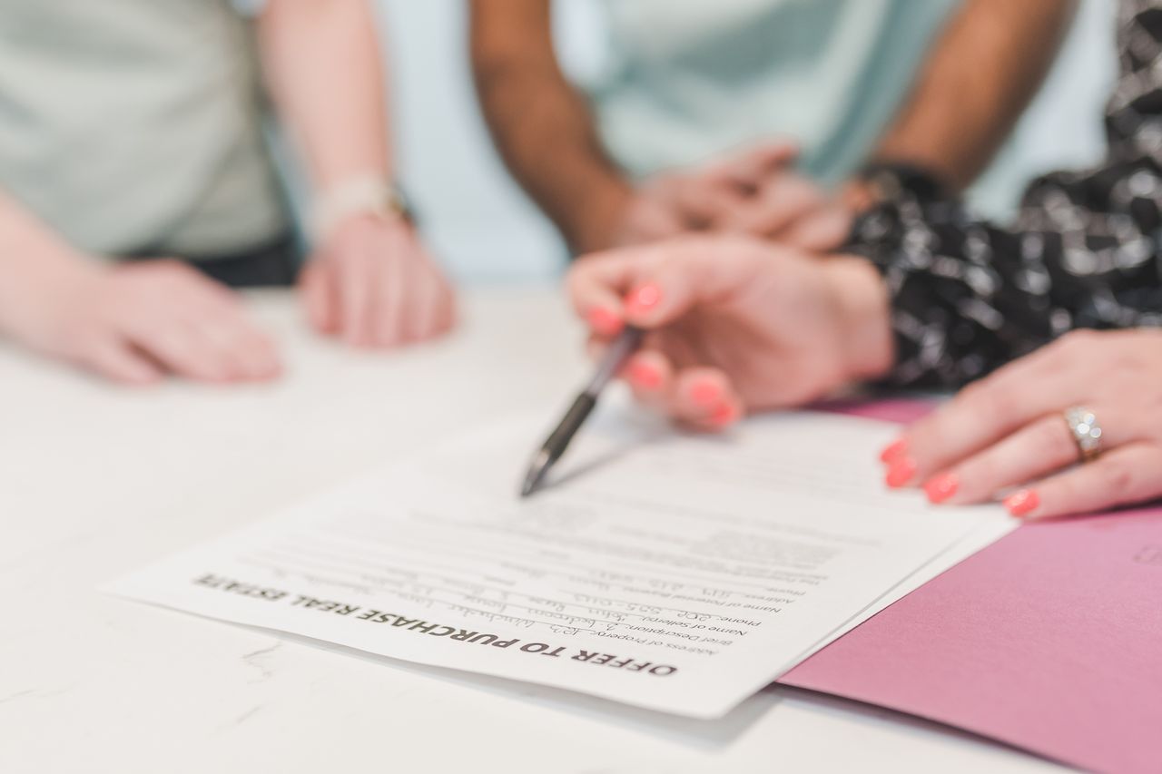 Home Close-up of people reviewing and signing an offer to purchase real estate document.